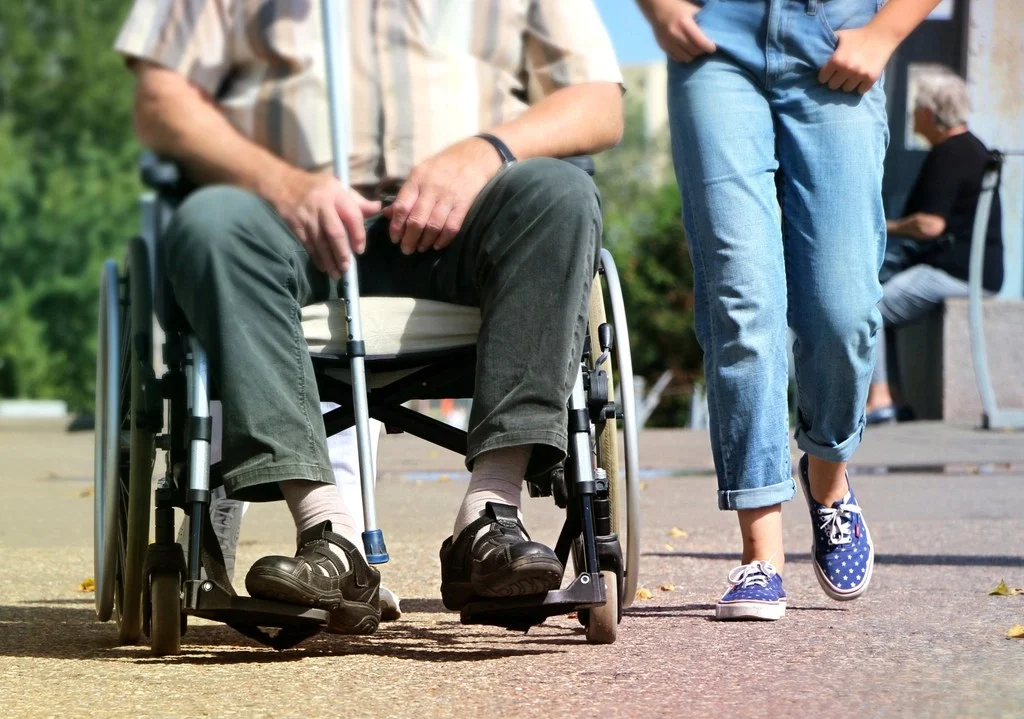 Persona en silla de ruedas paseando junto a un acompañante