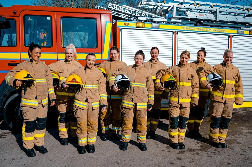 Equipo de bomberas delante de un camión de bomberos