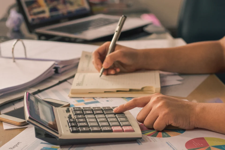 Persona haciendo cuentas con una calculadora y una libreta