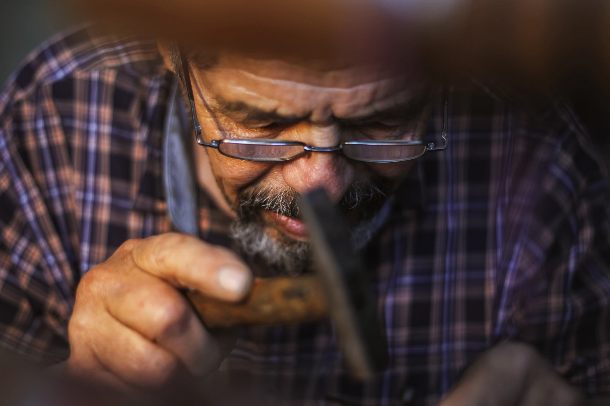Artesano mayor trabajando concentrado en su taller