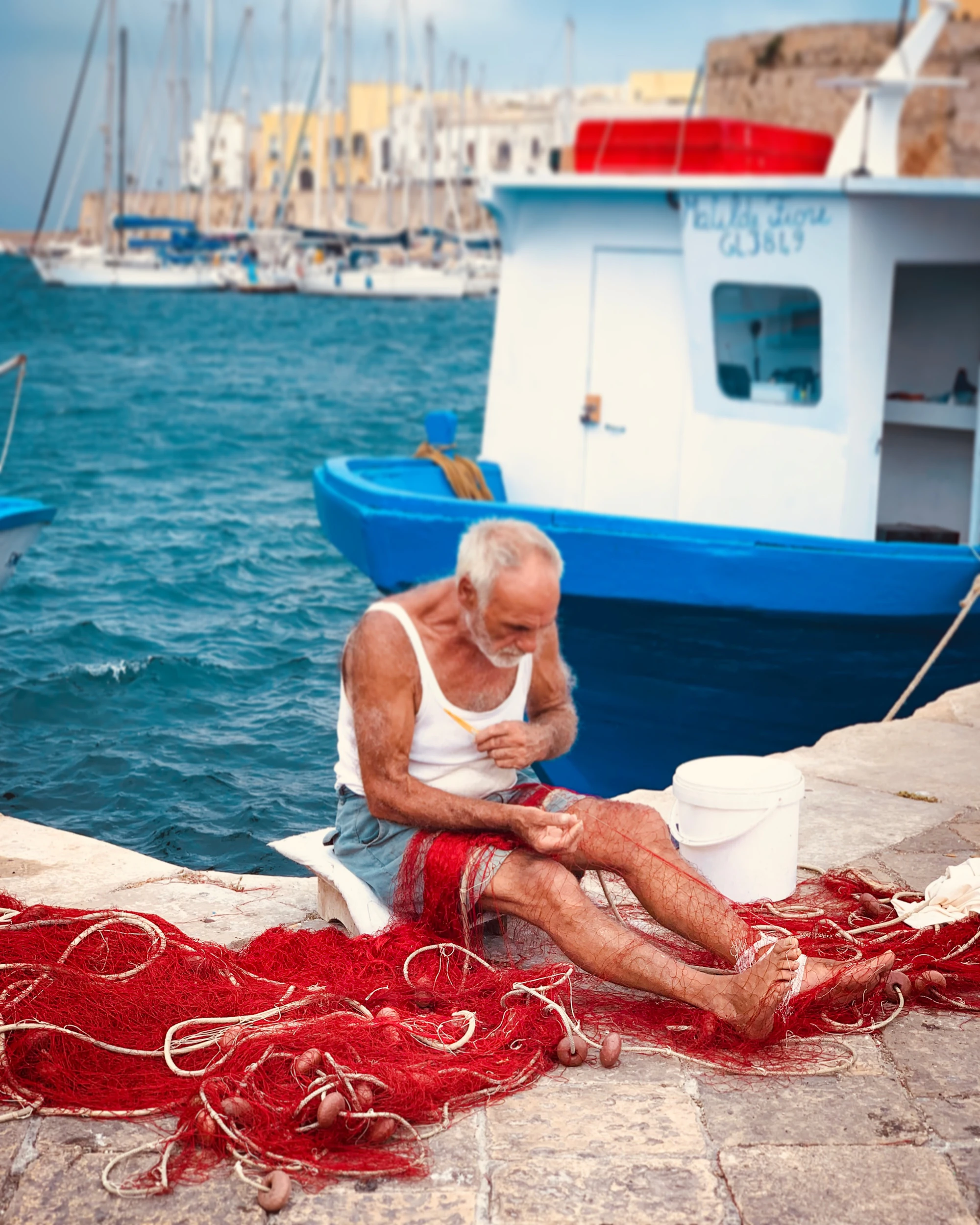 Hombre mayor reparando redes de pesca en un muelle
